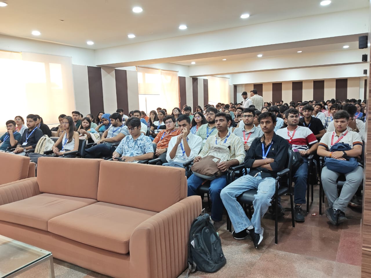 A seated audience of college students listening attentively in a seminar hall